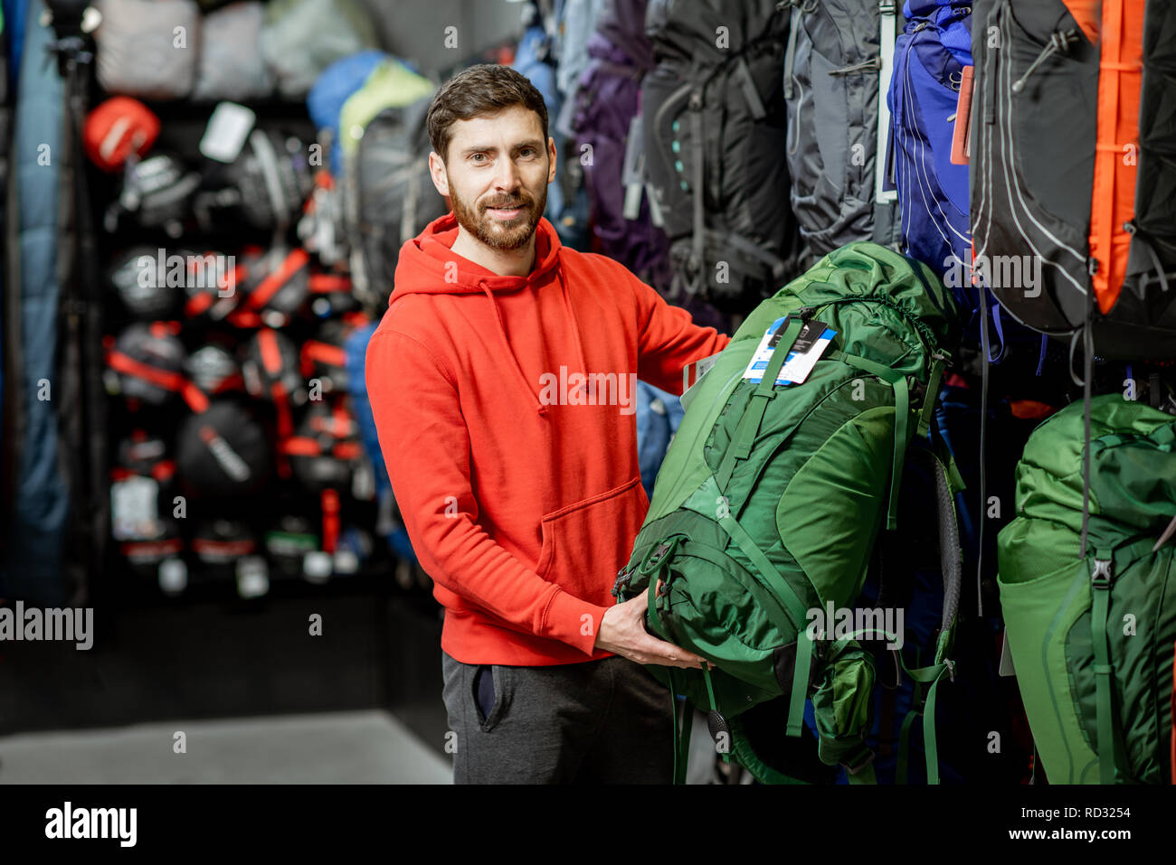 Man choosing some sports equipment looking on the backpacks for traveling in the sports shop Stock Photo