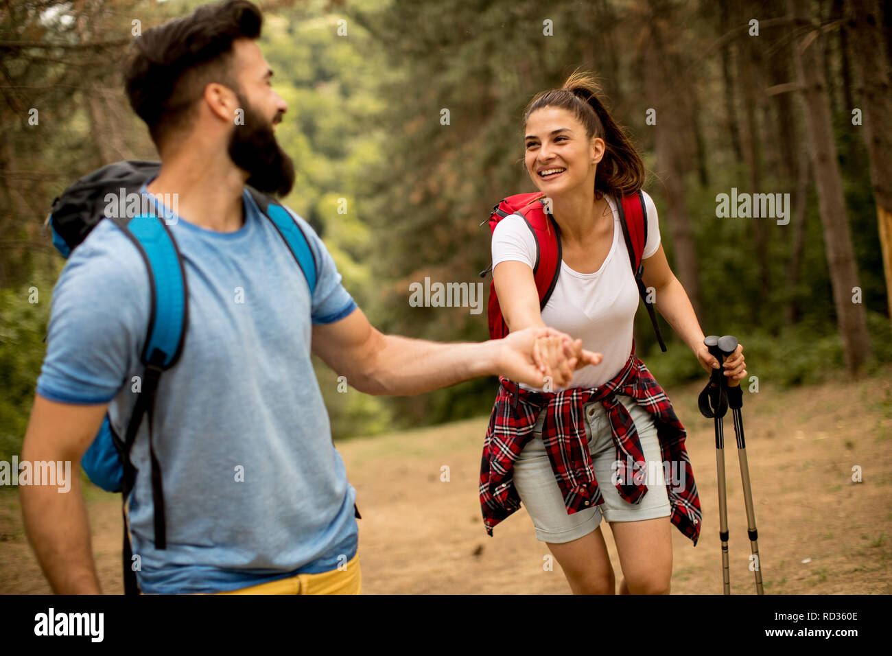 Young couple enjoying hiking in nature, holding hands and laughing ...