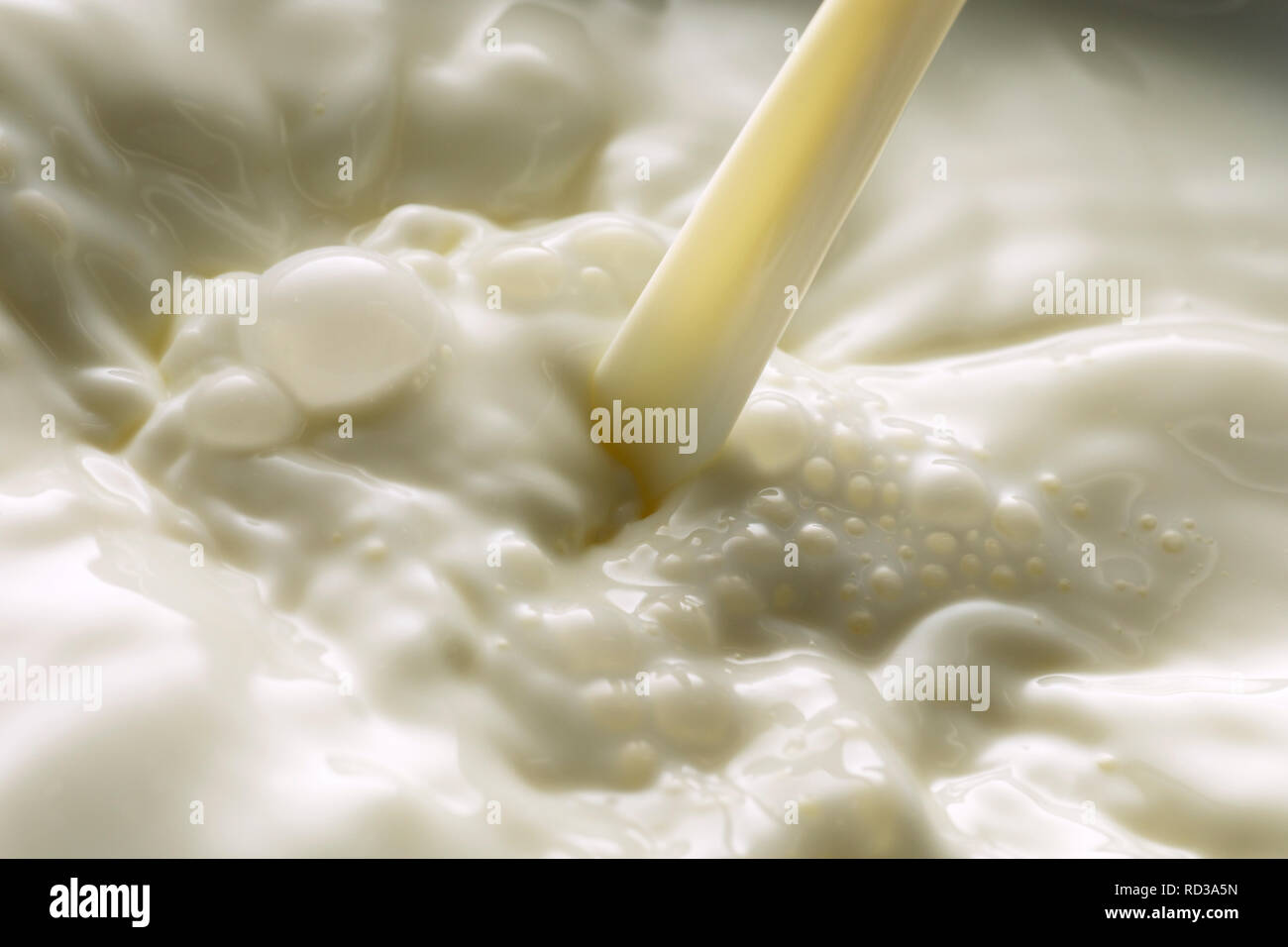 Close up of pouring milk making bubbles, studio shot Stock Photo