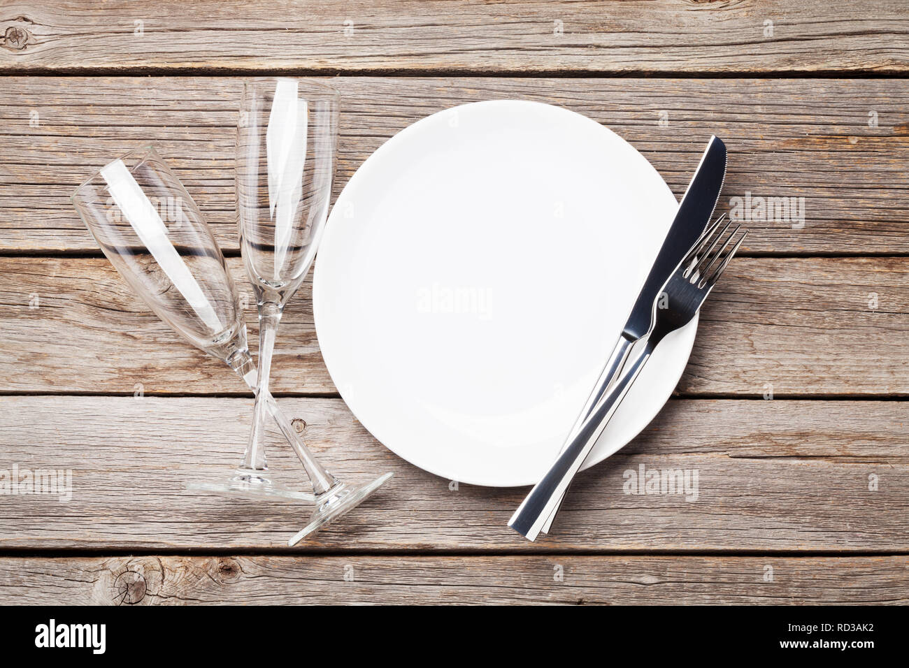 Table setting. Empty plate, knife, fork and champagne glasses. Top view