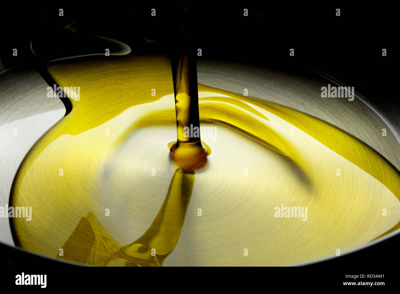 Close up of oil pouring into frying pan, studio shot Stock Photo