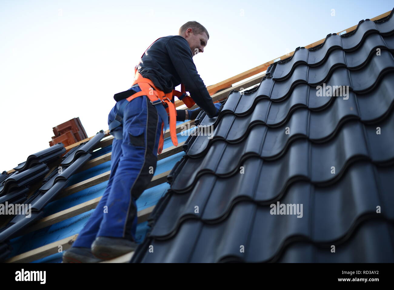 Dach neu mit schwarzen Dachsteinen eindecken. Dachdecker in Nord Deutschland, Handwerker Bauarbeiter in Lüneburg im Herbst Stock Photo
