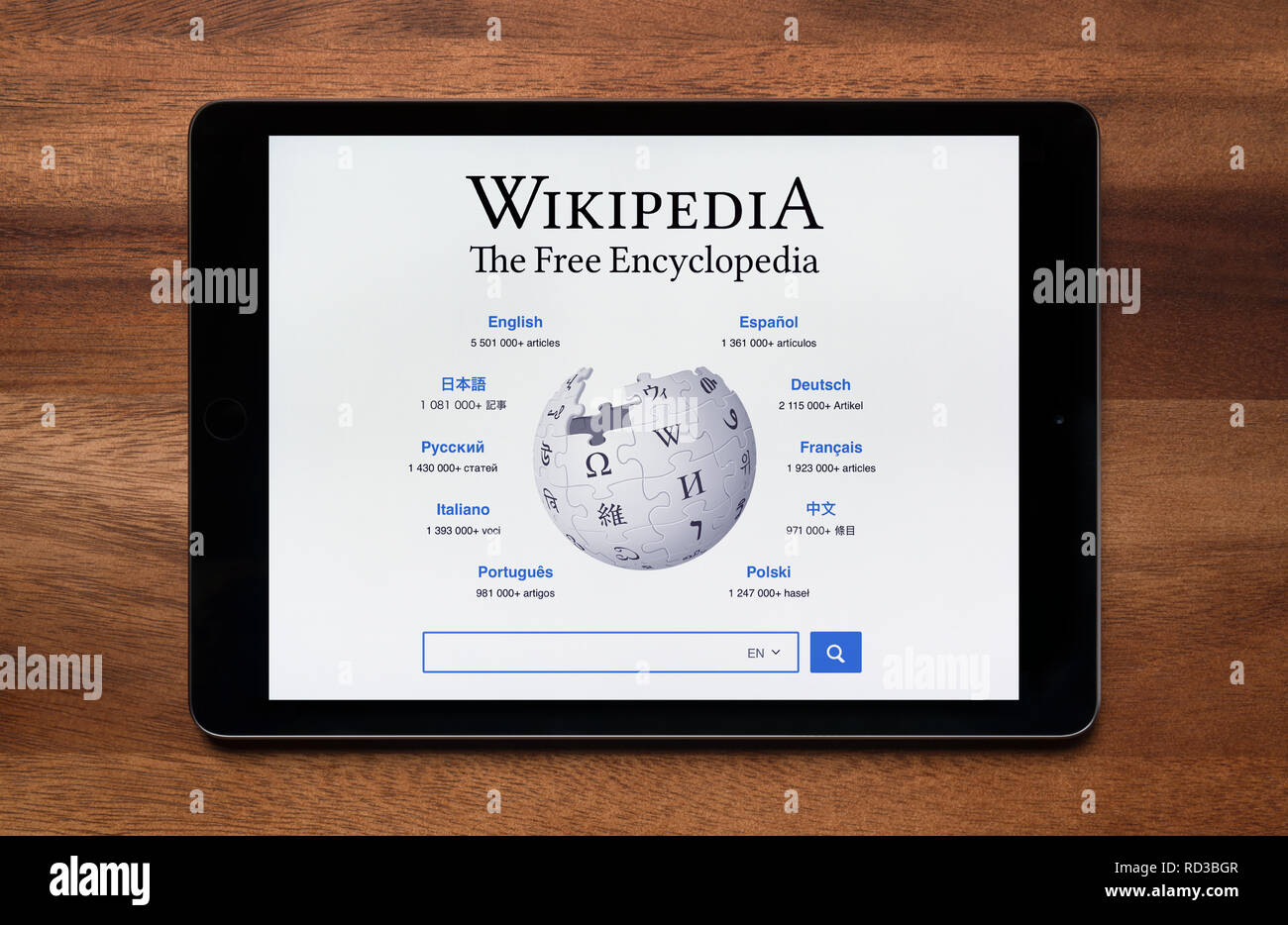 The website of Wikipedia is seen on an iPad tablet, which is resting on a wooden table (Editorial use only). Stock Photo
