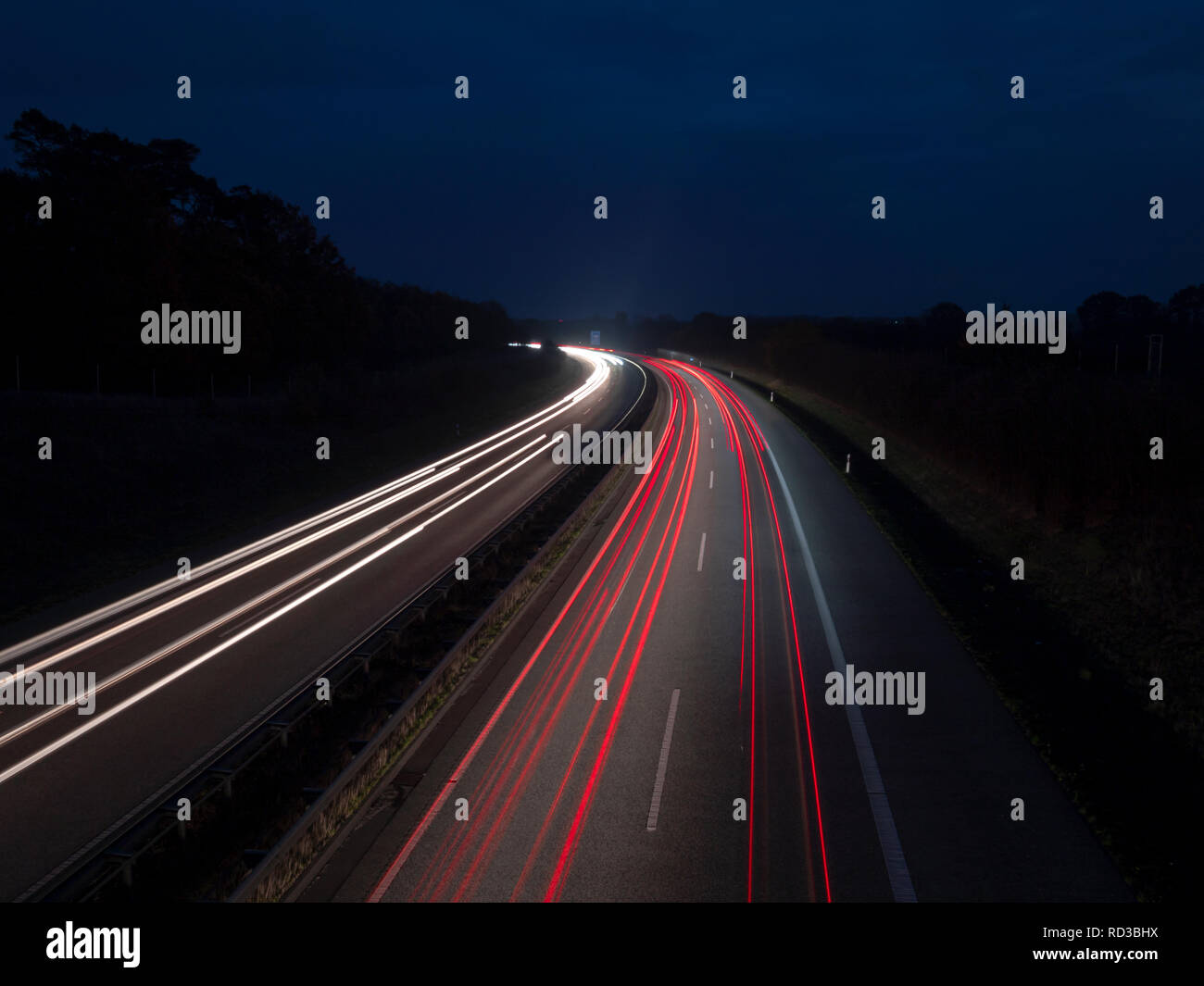 Red and white light tracks on the highway at the blue hour, corner lights and headlights Stock