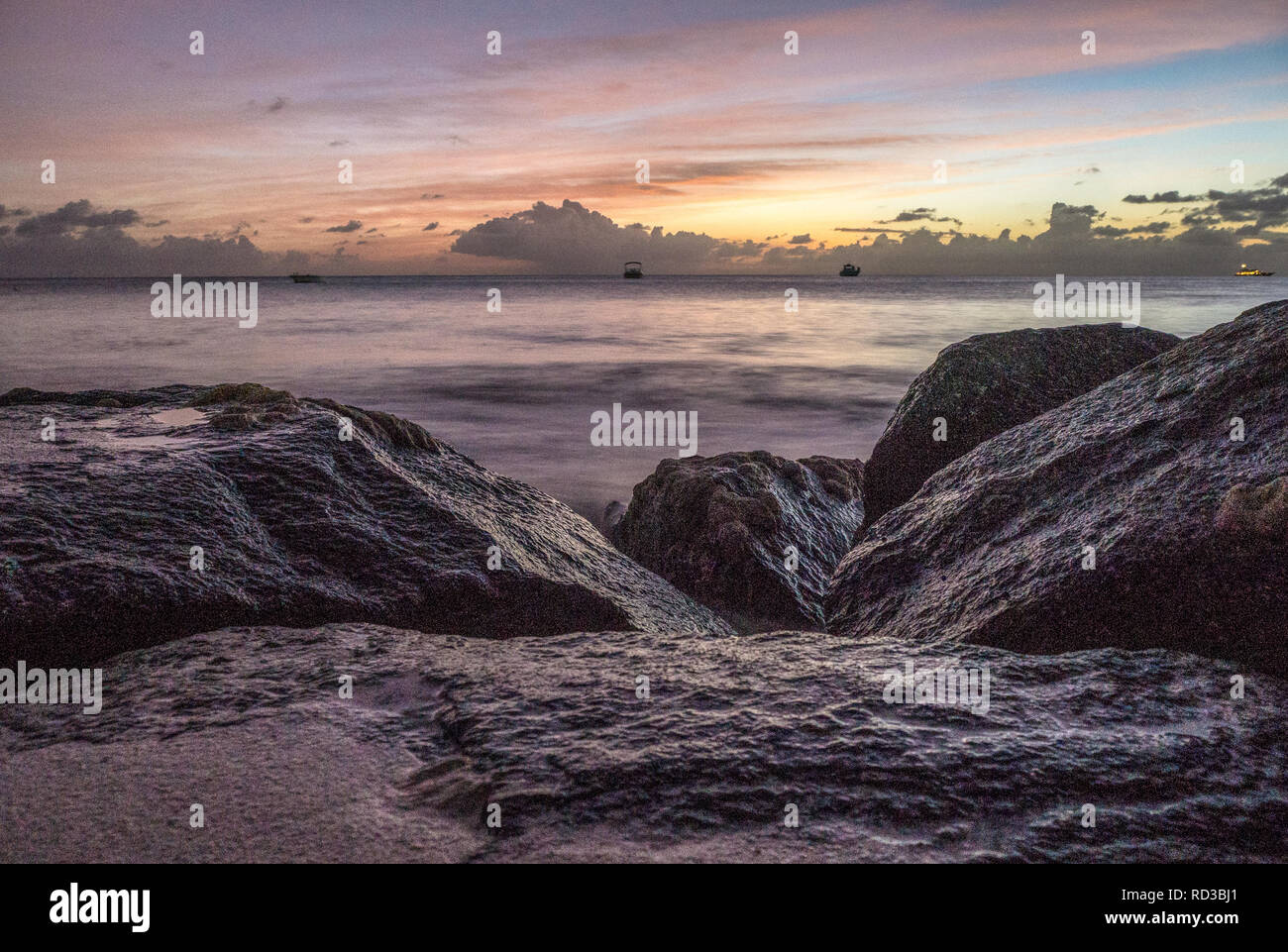 Rocks on Antiguan beach at sunset Stock Photo