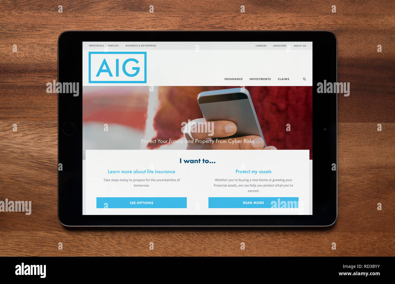 The website of AIG insurance is seen on an iPad tablet, which is resting on a wooden table (Editorial use only). Stock Photo