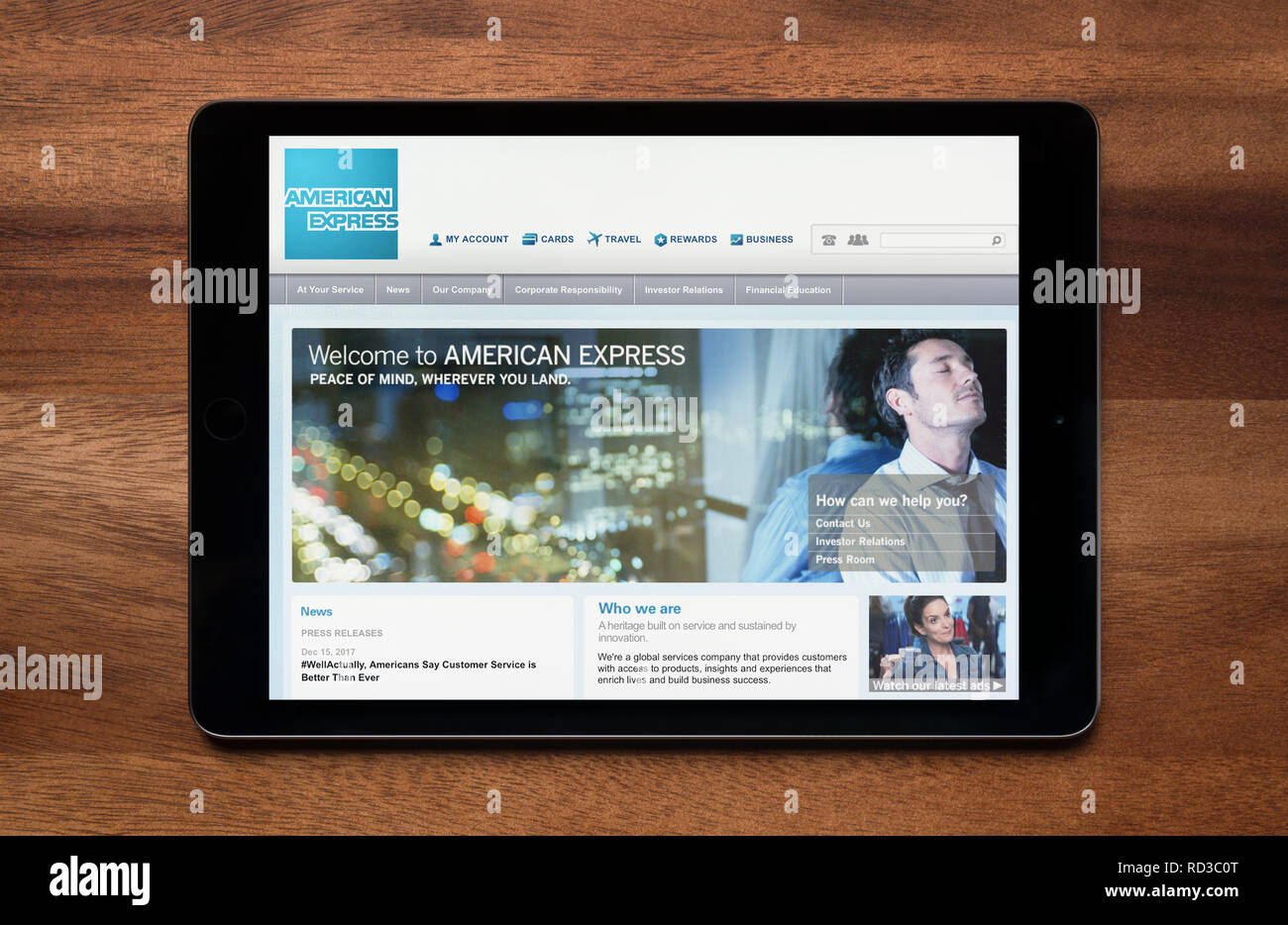 The website of American Express is seen on an iPad tablet, which is resting on a wooden table (Editorial use only). Stock Photo