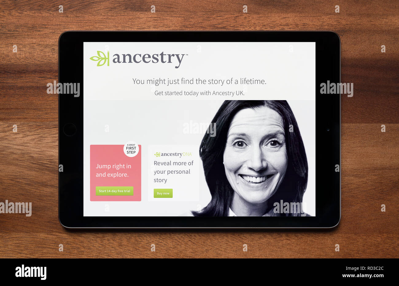 The website of Ancestry is seen on an iPad tablet, which is resting on a wooden table (Editorial use only). Stock Photo