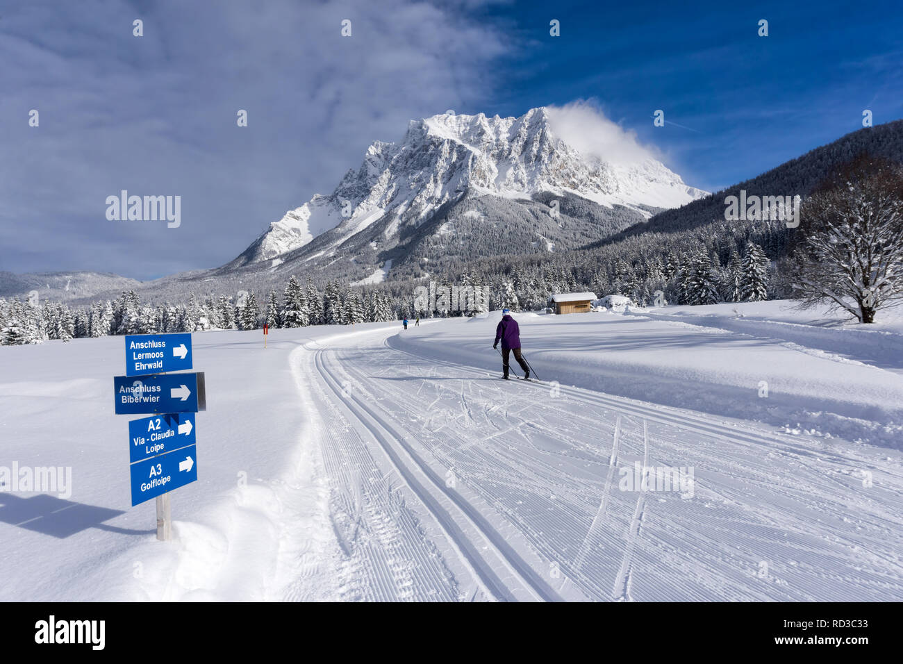 Winter mountain landscape with groomed ski tracks and blue sky in sunny day. Ehrwald, Tirol, Alps, Austria, Zugspitze Massif  in background. Stock Photo
