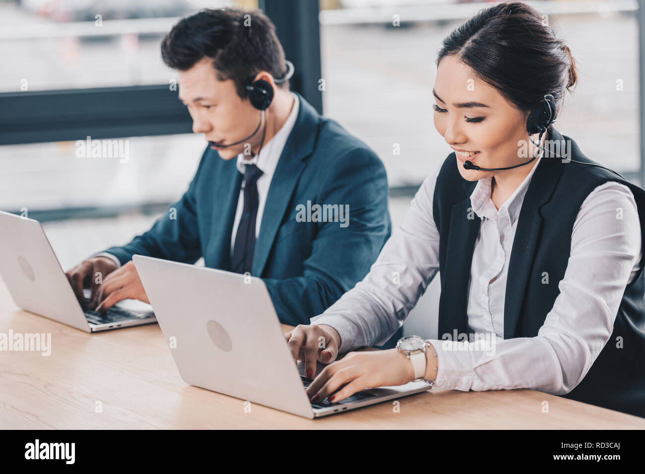 young kazakh coworkers in headsets using laptops at workplace Stock Photo