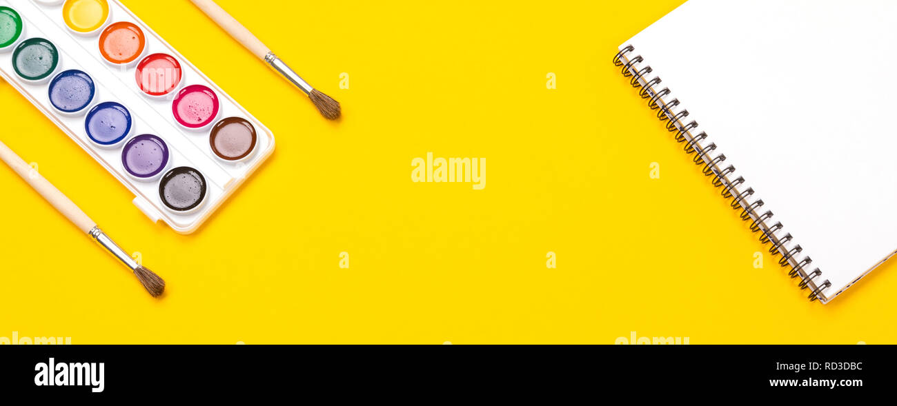 Watercolor paints and brushes with canvas for painting with copyspace on yellow background Stock Photo