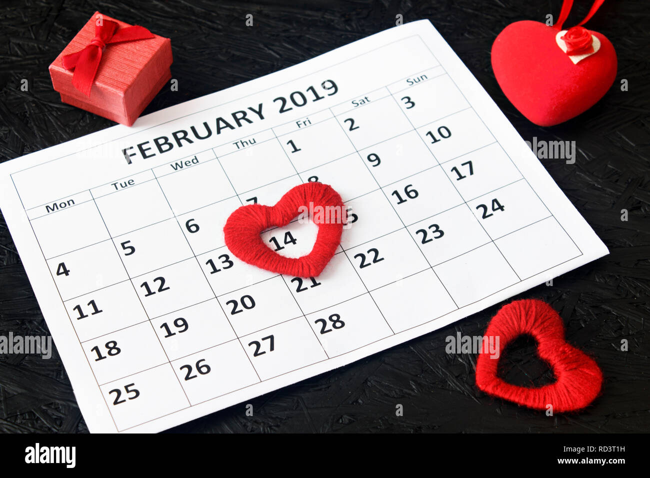 Calendar page with red hearts and a gift on February 14, Valentine's Day on  a black background. Valentine card Stock Photo - Alamy
