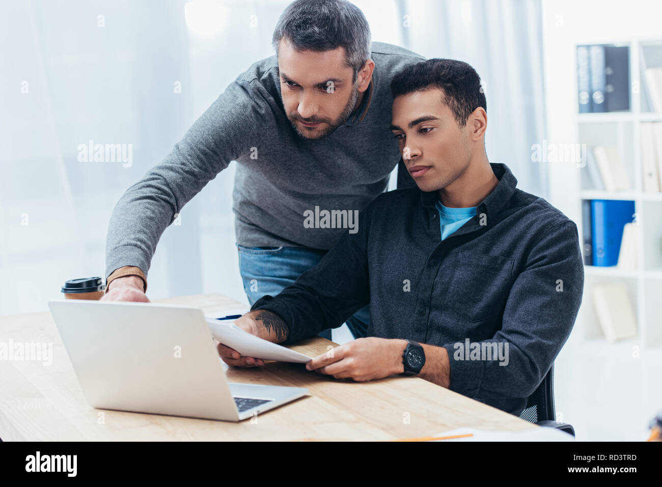 two focused businessmen working with papers and laptop in office Stock Photo