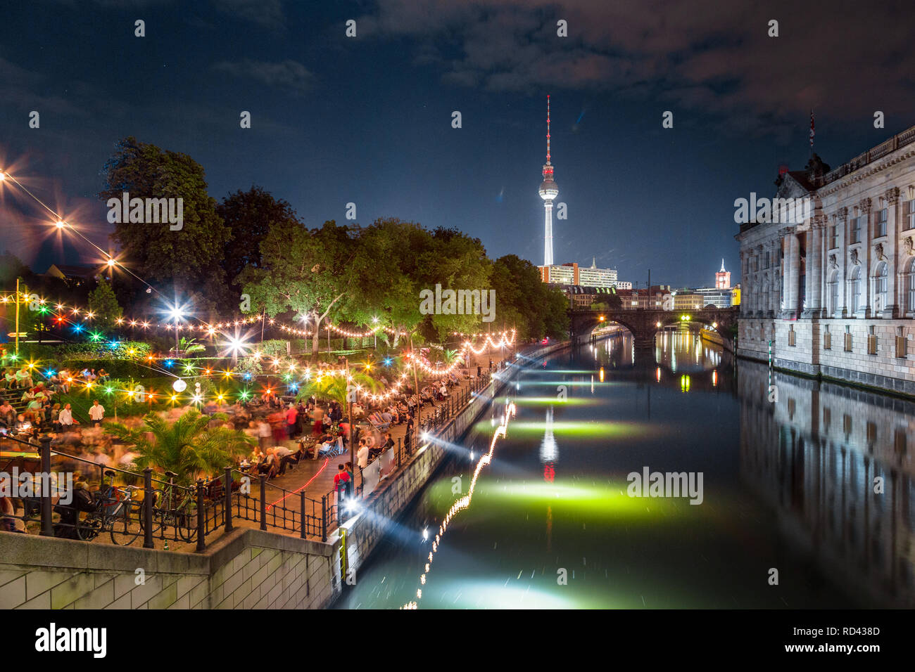 People dancing at summer Strandbar beach party near Spree river at Museum Island with famous TV tower in the background at night, Berlin, Germany Stock Photo