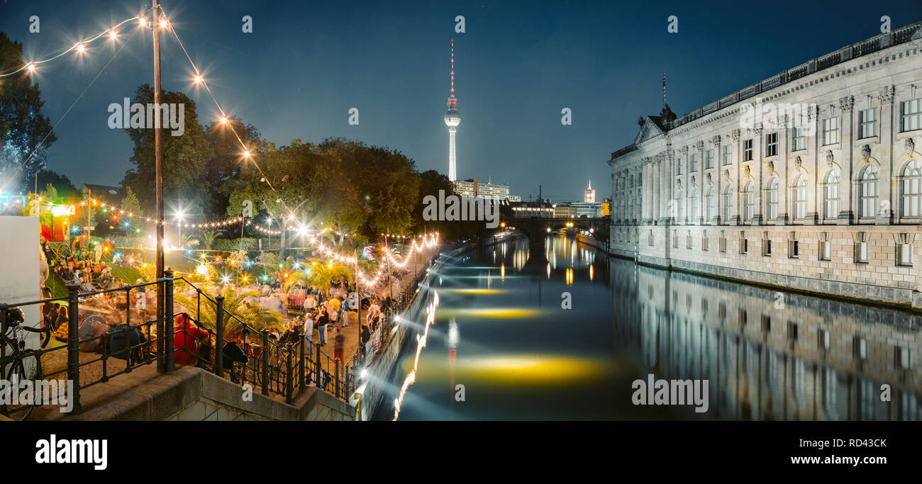 People dancing at summer Strandbar beach party near Spree river at Museum Island with famous TV tower in the background at night, Berlin, Germany Stock Photo