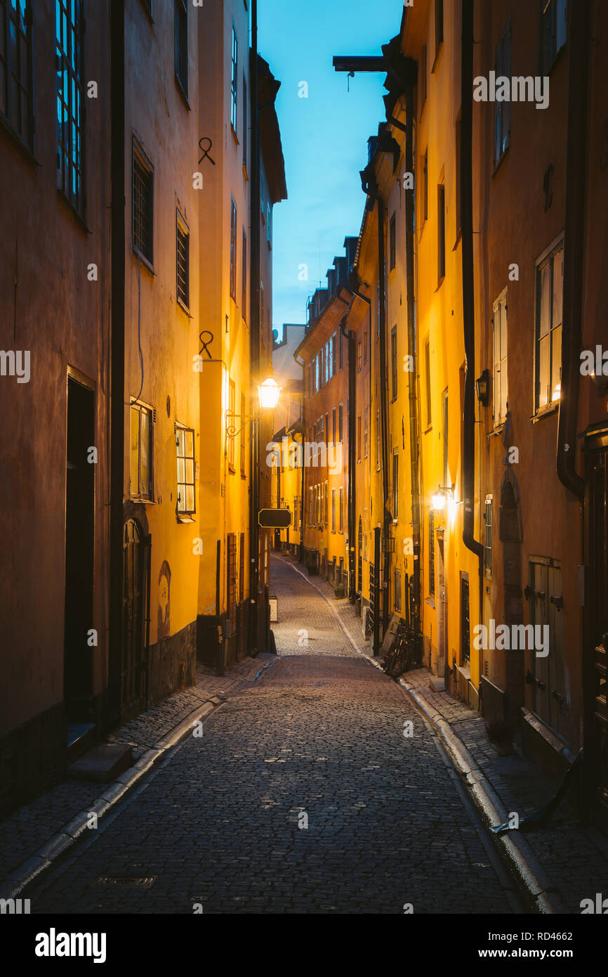 Classic twilight view of tradtional houses in beautiful alleyway in Stockholm's historic Gamla Stan (Old Town) illuminated during blue hour at dusk Stock Photo