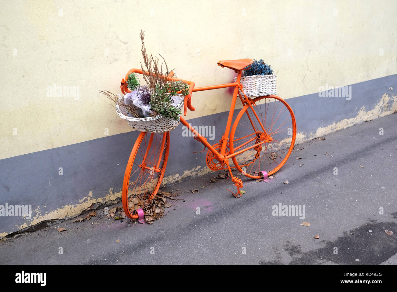 Retro style sport bike color orange with flower baskets as decoration outdoor near the wall side view Stock Photo
