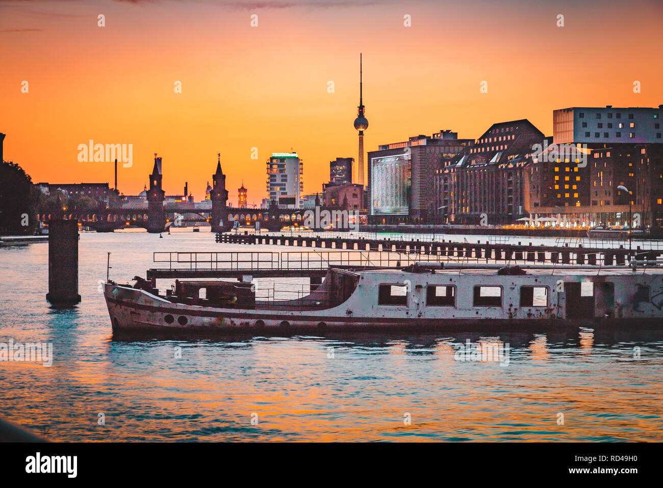 Panoramic view of Berlin skyline with famous TV tower and Oberbaum Bridge with old ship wreck lying in river Spree at dusk, Berlin, Germany Stock Photo