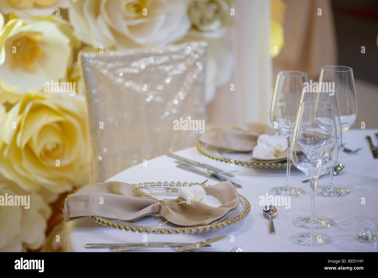 Sitting arrangement at a formal event or fine dining restaurant featuring transparent plates with golden details, with elegan glassware and silverware Stock Photo