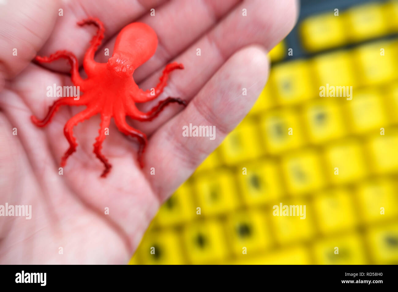 Octopus figurine on a hand and computer keyboard, data leech Stock Photo