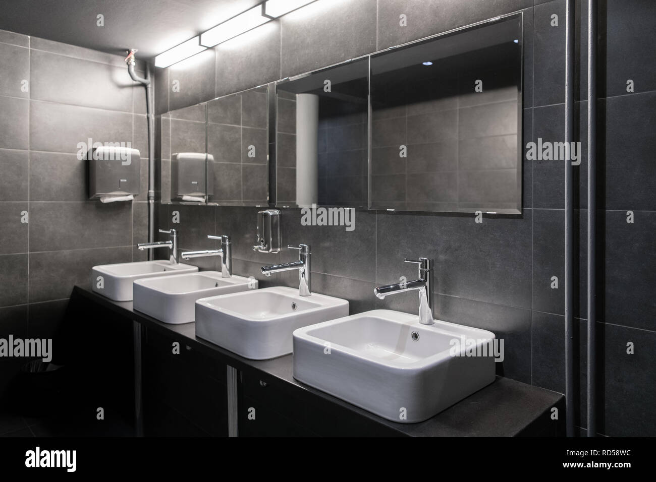 Faucets with washbasin in public restroom in grey colors Stock Photo