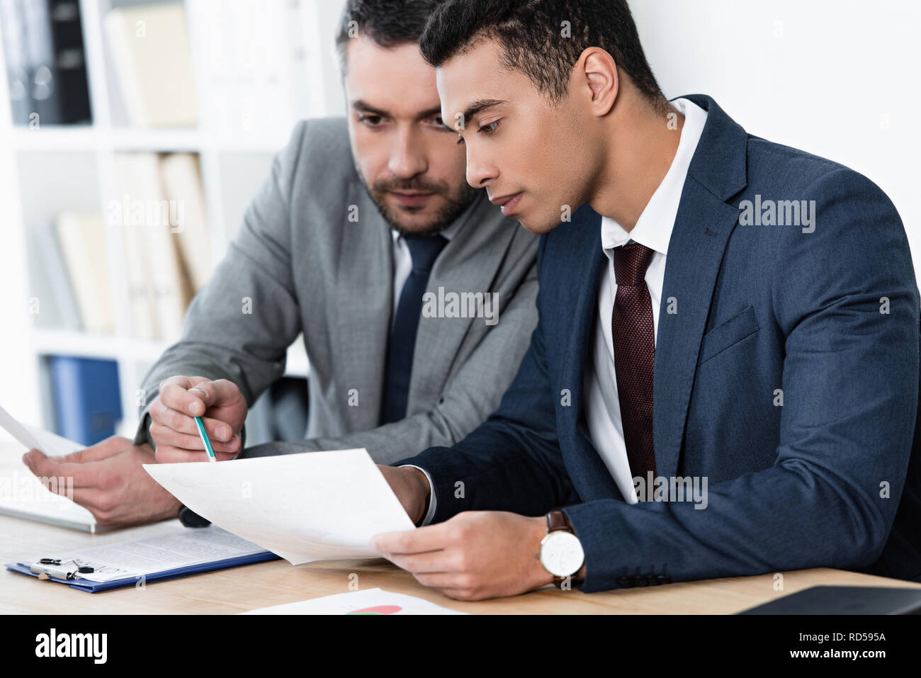 two focused businessmen working with papers in office Stock Photo