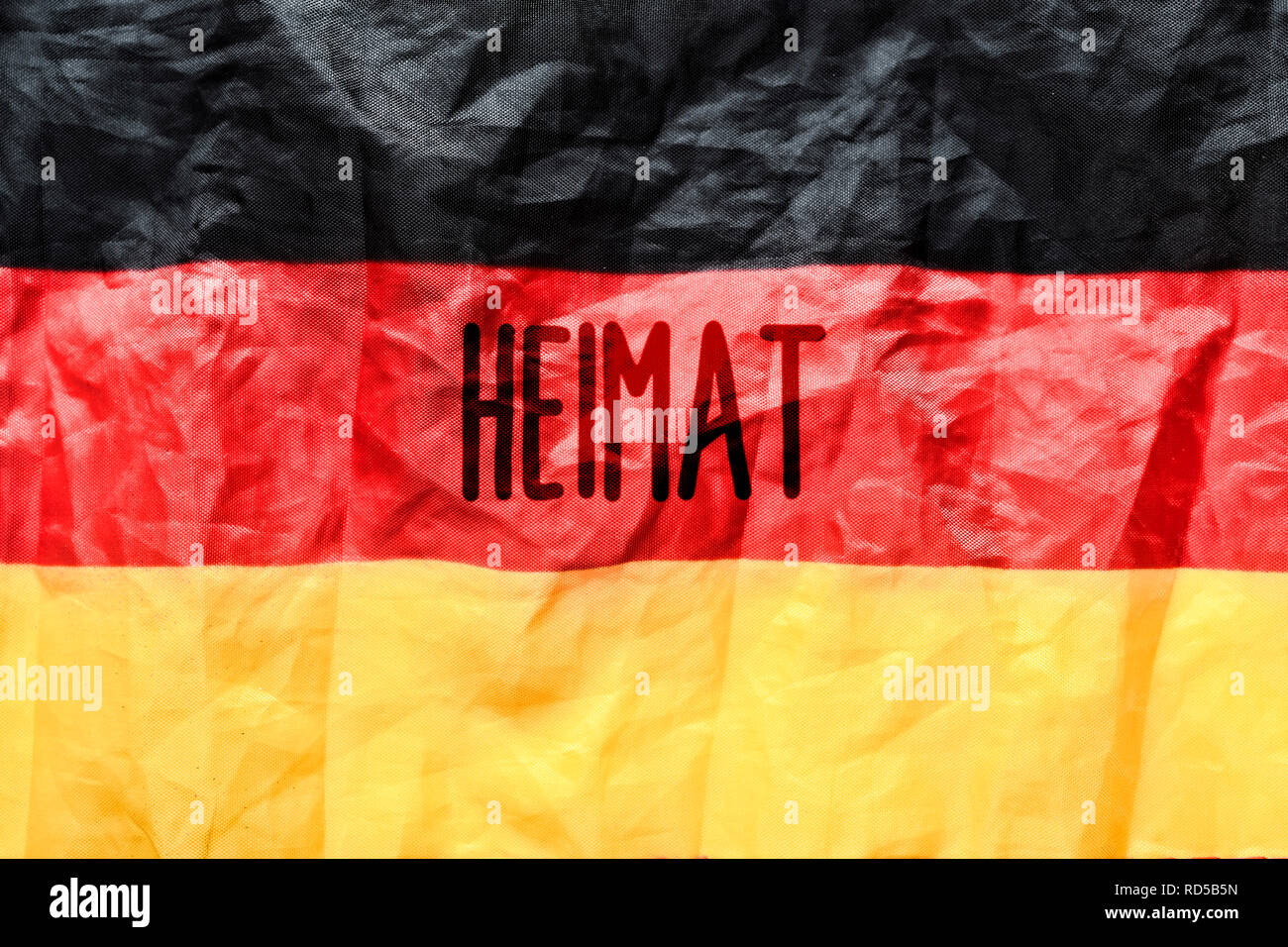 The word Native country on crumpled Germany flag, home concept, Das Wort Heimat auf zerknitterter Deutschlandfahne, Heimatbegriff Stock Photo