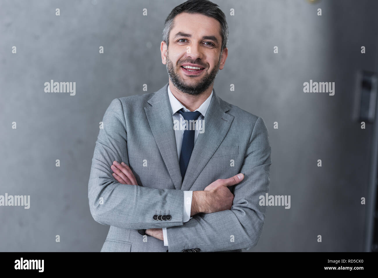 confident handsome businessman standing with crossed arms and smiling ...