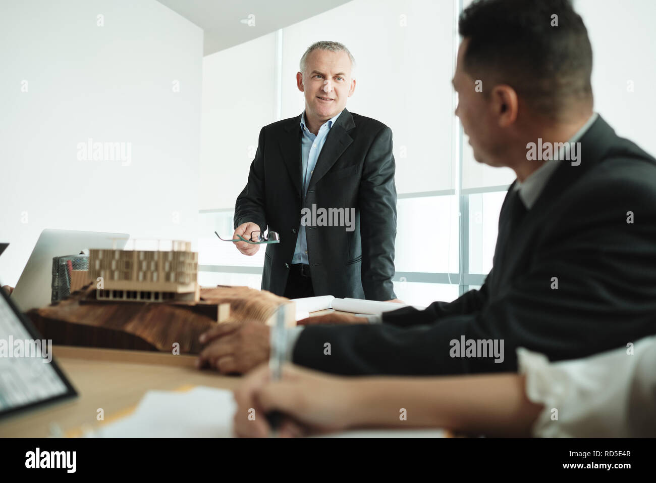 Architect Showing Miniature Building At Business Meeting With Client Stock Photo