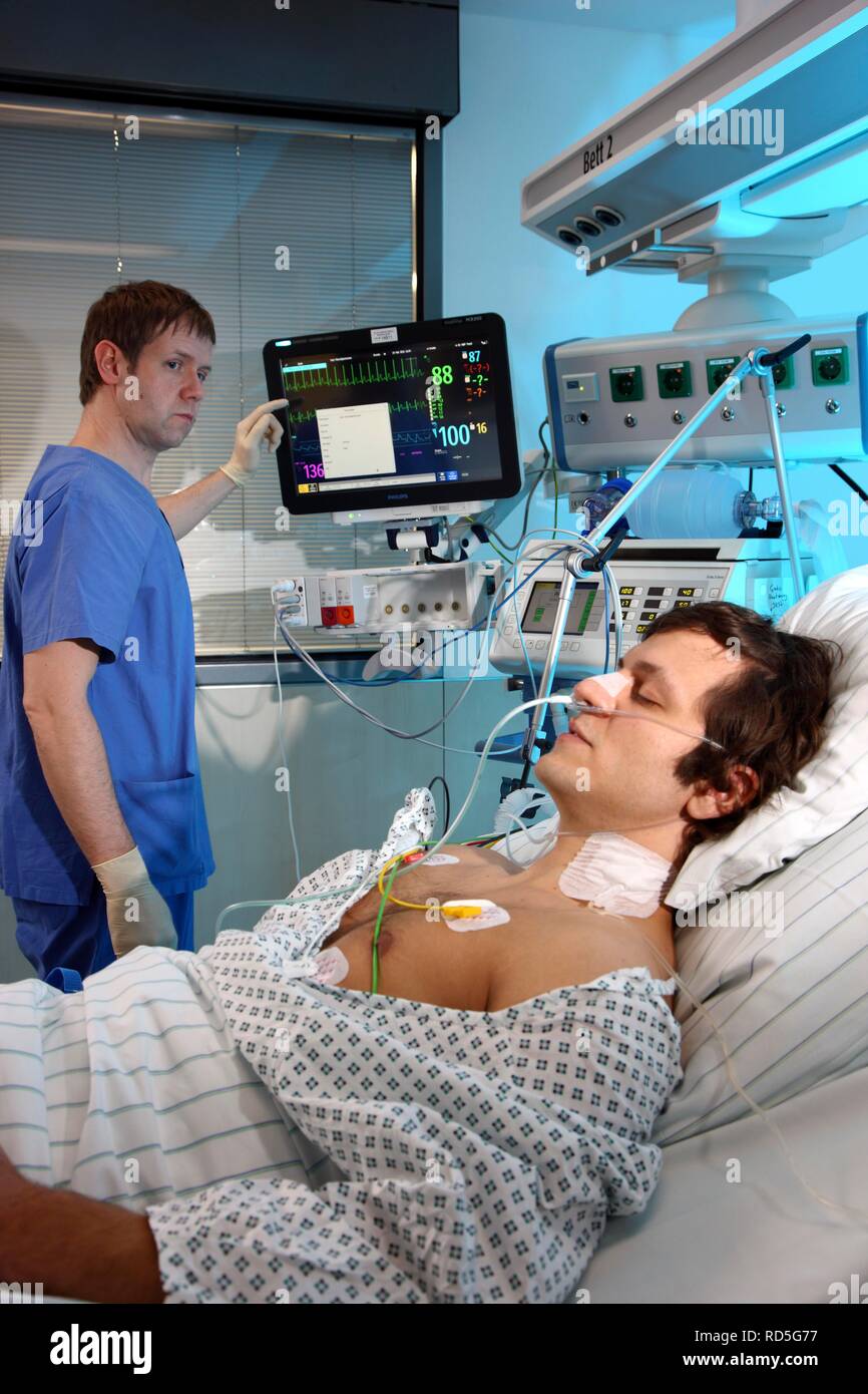 Male intensive care nurse looking after a patient lying in a special bed, medical treatment and artificial respiration of the Stock Photo