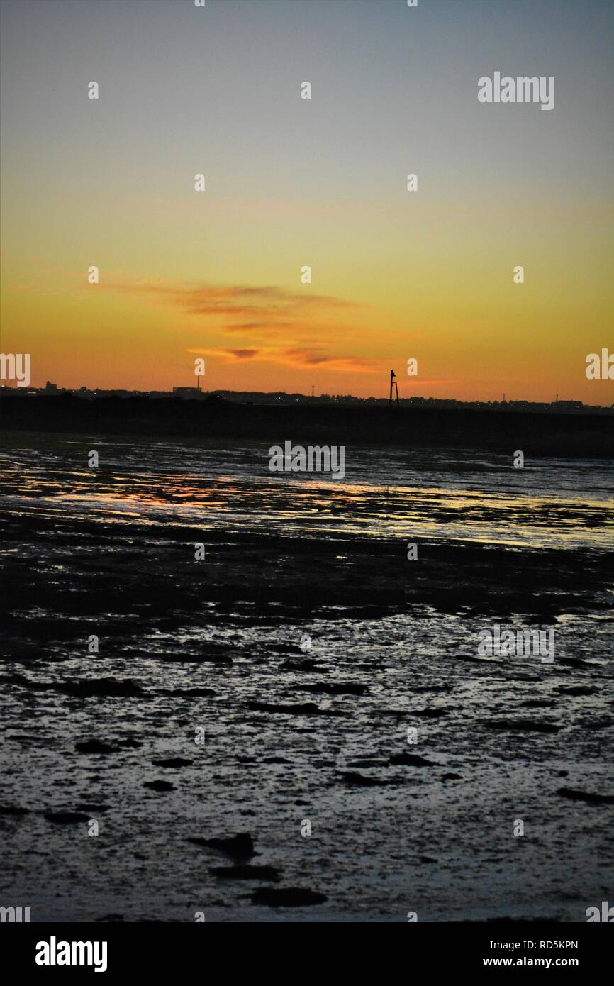 Sunset over the muddy estuary foreshore Stock Photo
