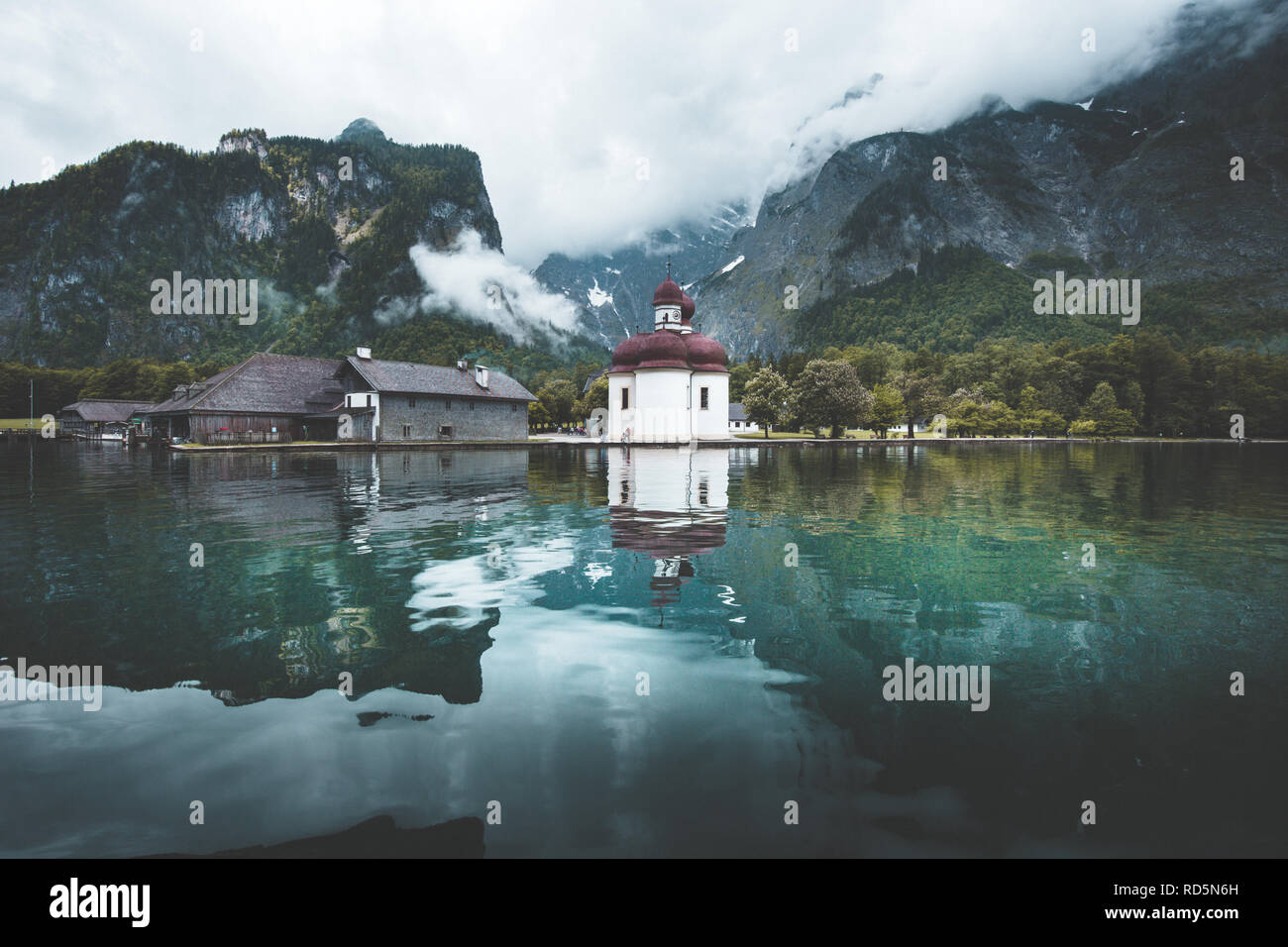 Classic view of Lake Konigssee with world famous Sankt Bartholomae pilgrimage church and Watzmann mountain on a beautiful sunny day in summer Stock Photo