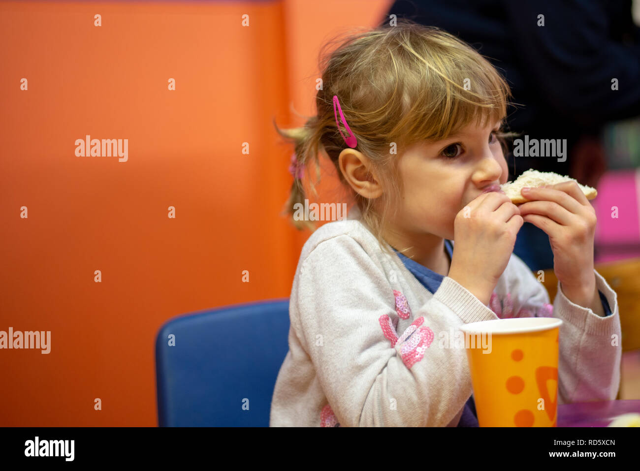 Girl eating sandwich at birthday party Stock Photo