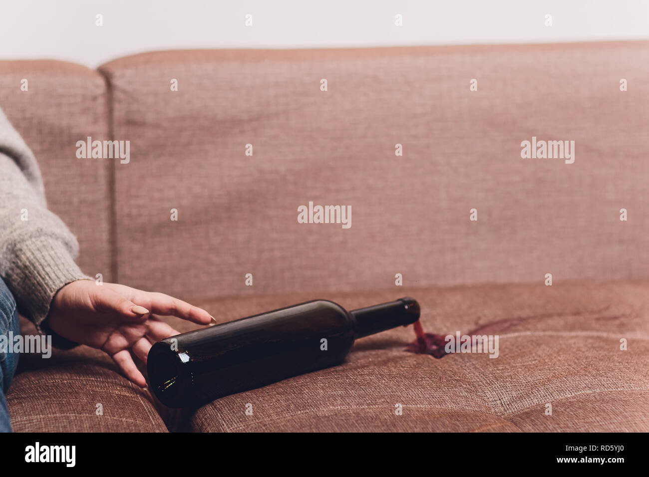 Red wine spilled on a brown couch sofa. dark bottle of red wine dropped ...