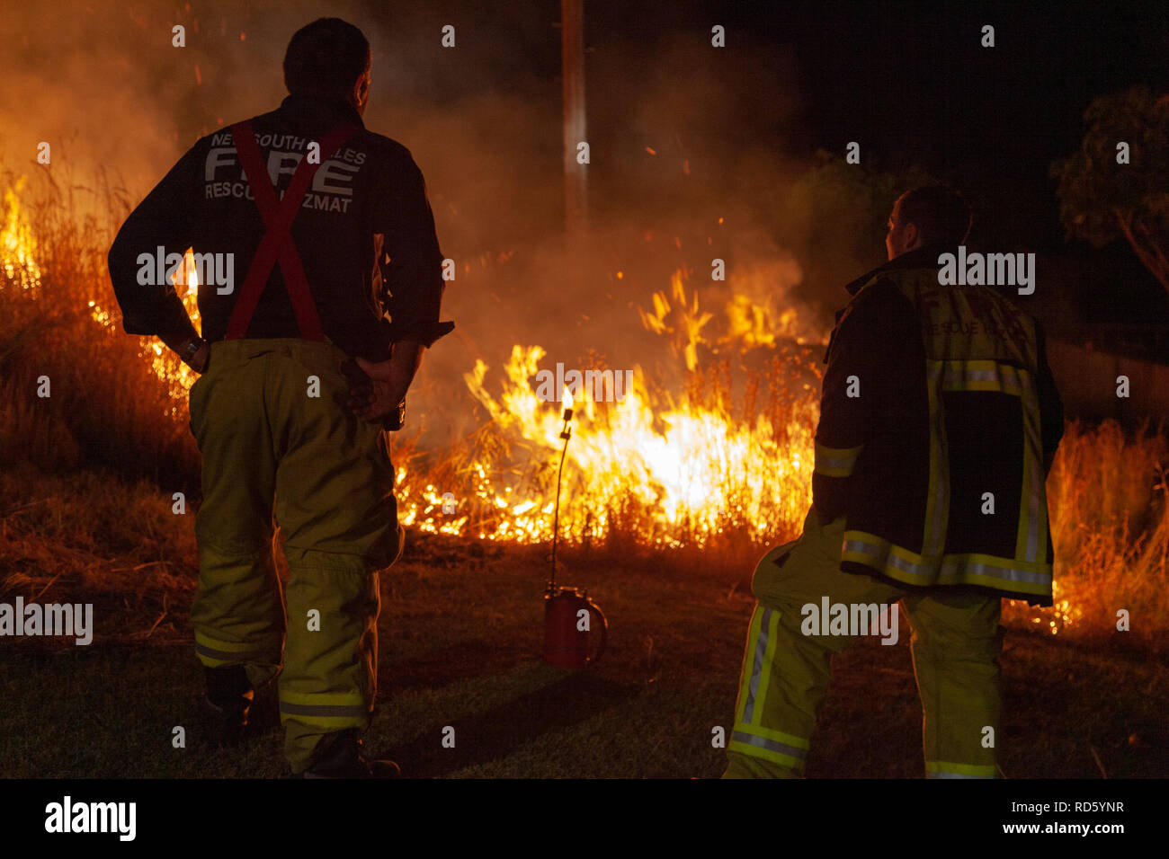 Teralba, NSW/Australia - October 24, 2012: Firemen or firefighters supervising backburning and extinguishing a wildfire grass and bushfire to protect  Stock Photo