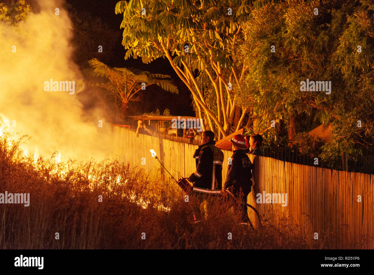 Teralba, NSW/Australia - October 24, 2012: Firemen or firefighters backburning and extinguishing a wildfire grass and bushfire to protect residents of Stock Photo