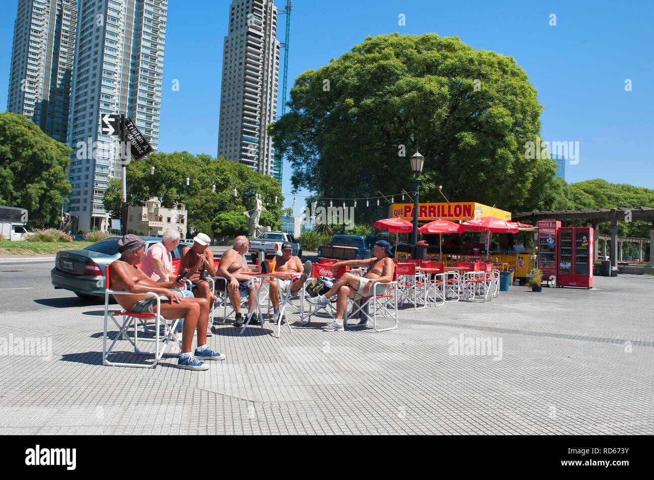 Group of Argentinean men resting beside a kiosk, skyscrapers at the back, Puerto Madero district, Buenos Aires, Argentina Stock Photo