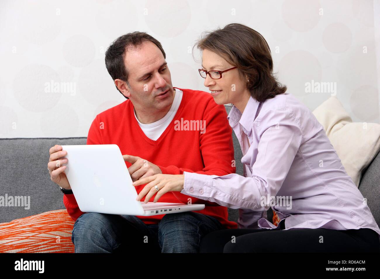 Couple, man, woman, about 45 years old, surfing the Internet on a laptop at home Stock Photo