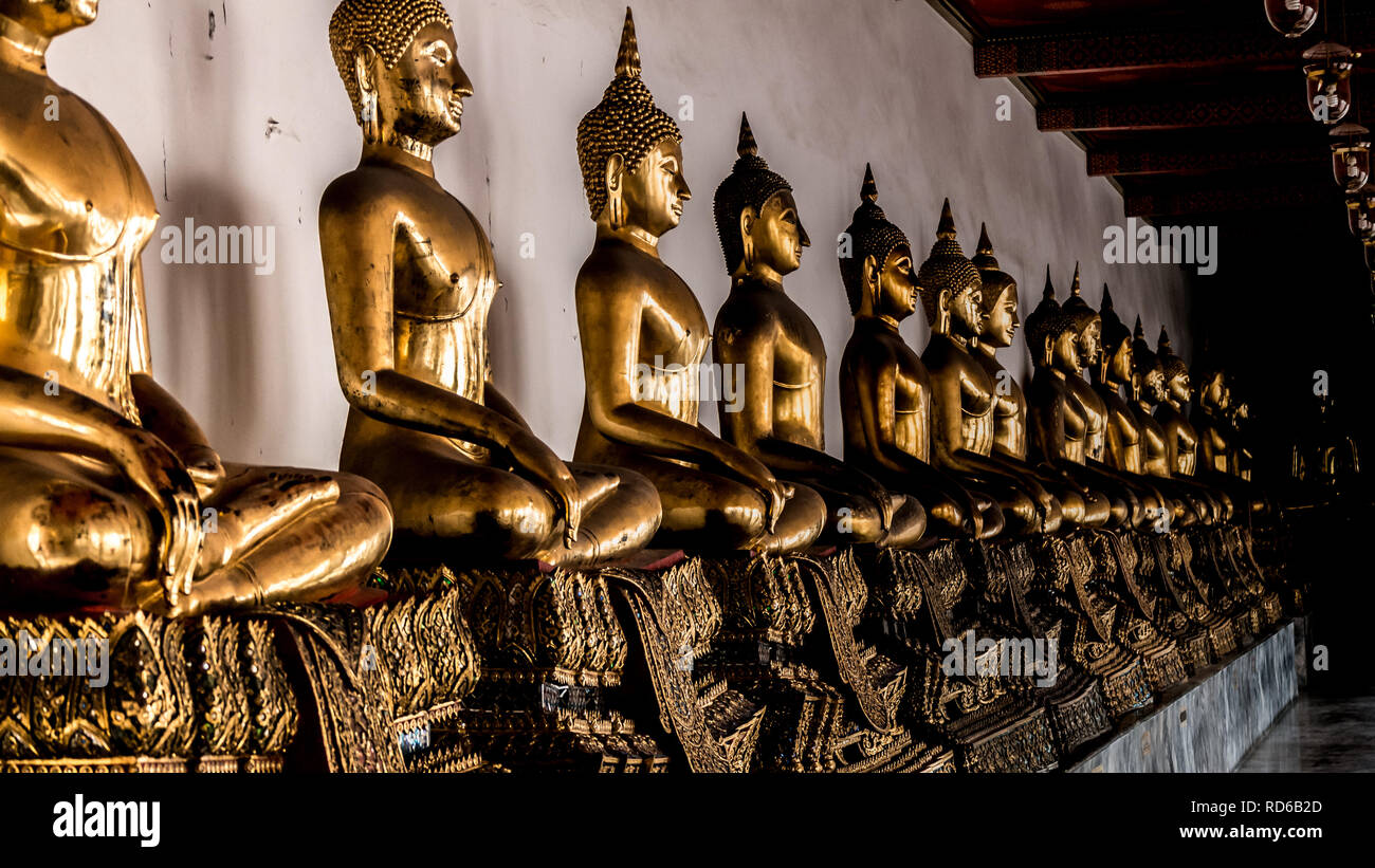 A line of Golden sitting Buddha Statues at the Wat Pho Buddhist temple ...