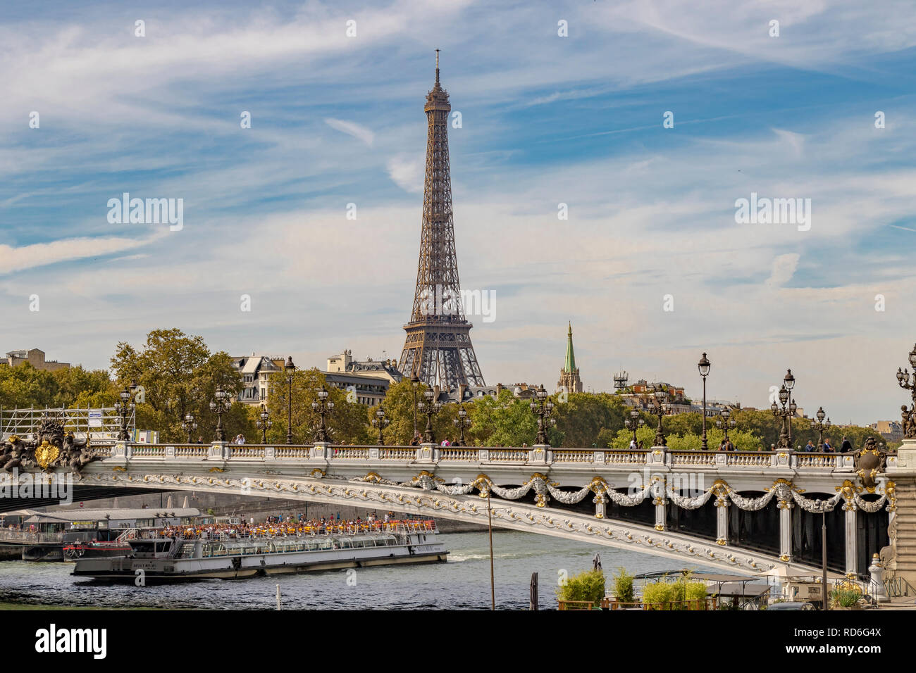 A River Seine sightseeing boat passes beneath Pont Alexandre III bridge with The Eiffel Tower in the distance in summer time ,Paris ,France Stock Photo