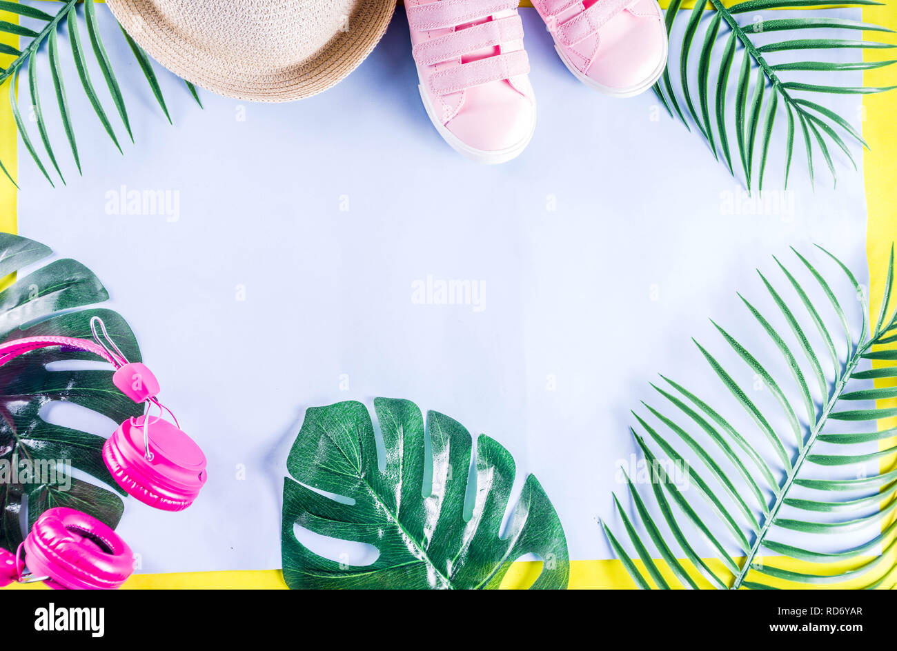 Colorful summer vacation and holiday flat-lay. Straw hat, sunglasses, palm and monstera leaves on bright blue yellow background, top view, copy space Stock Photo