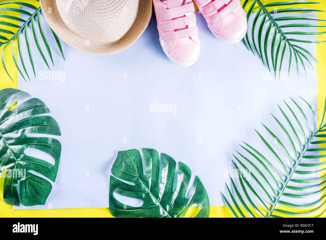 Colorful summer vacation and holiday flat-lay. Straw hat, sunglasses, palm and monstera leaves on bright blue yellow background, top view, copy space Stock Photo