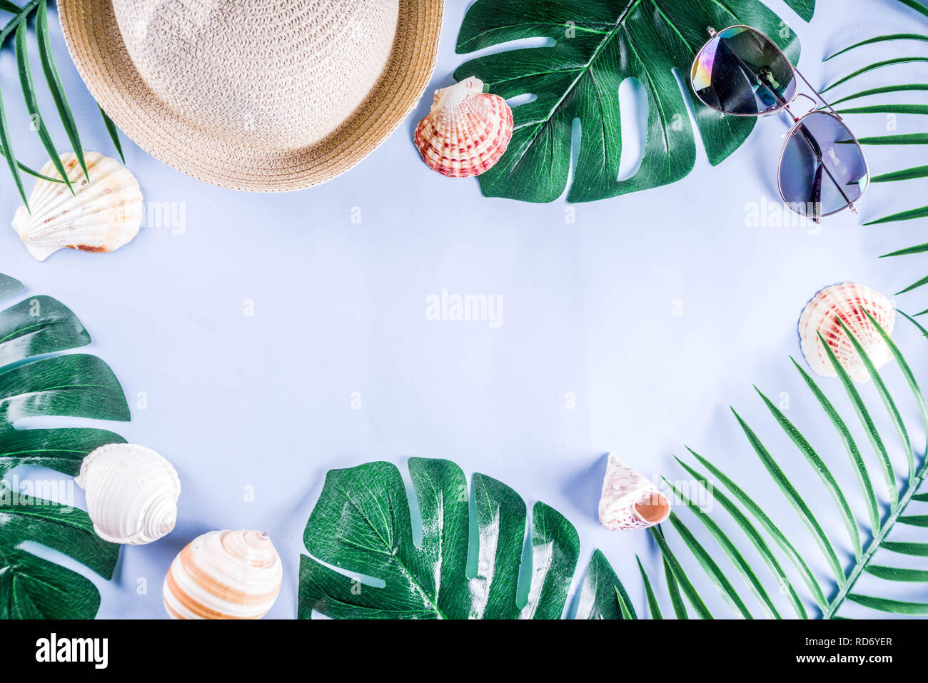 Colorful summer vacation and holiday flat-lay. Straw hat, sunglasses, palm and monstera leaves on bright blue yellow background, top view, copy space Stock Photo