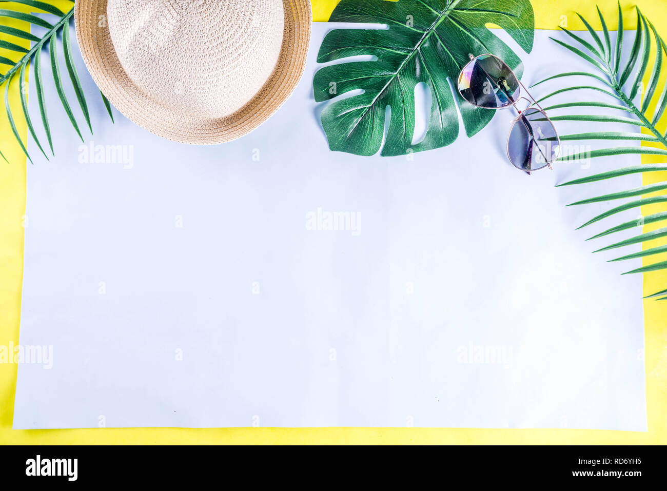 Colorful summer vacation and holiday flat-lay. Straw hat, sunglasses, palm and monstera leaves on bright blue yellow background, top view, copy space Stock Photo