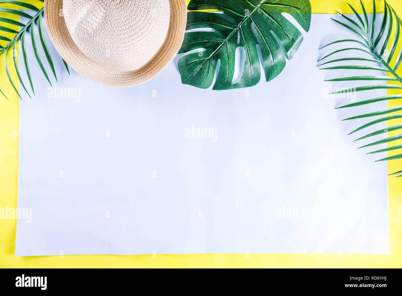 Colorful summer vacation and holiday flat-lay. Straw hat, sunglasses, palm and monstera leaves on bright blue yellow background, top view, copy space Stock Photo