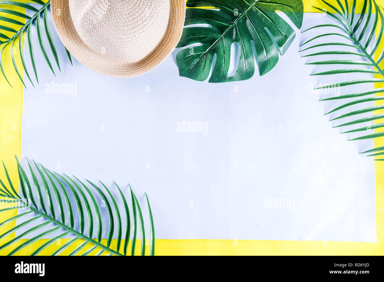 Colorful summer vacation and holiday flat-lay. Straw hat, sunglasses, palm and monstera leaves on bright blue yellow background, top view, copy space Stock Photo