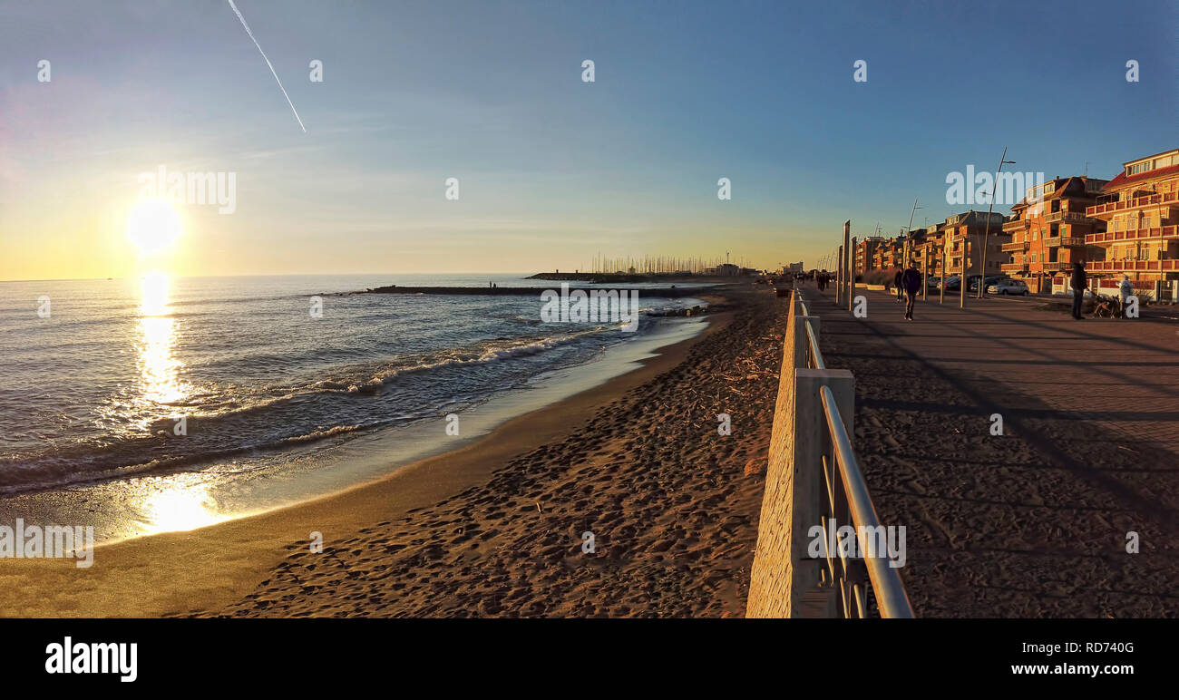 Ostia Lido Rome, Italy - January 15, 2019::Roman coast street view in Ostia Lido at sunset time with people walking and enjoy the beautiful winter day Stock Photo