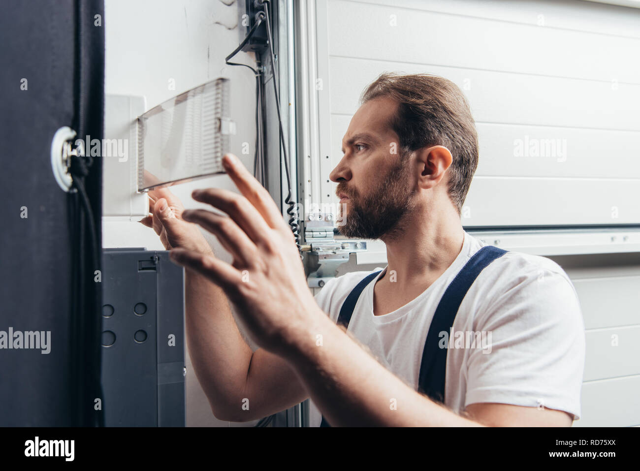 concentrated male bearded handyman checking electrical box Stock Photo