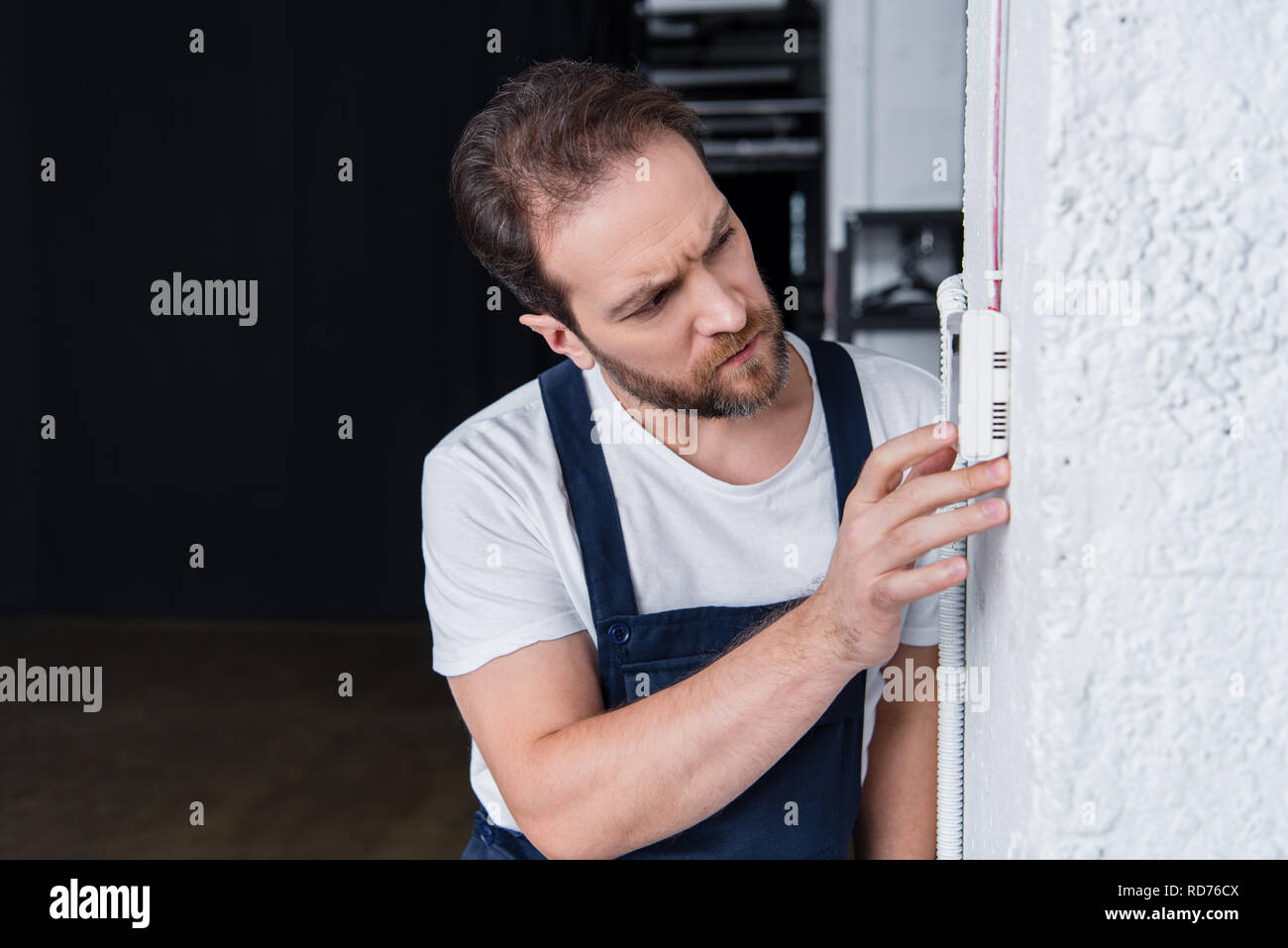 concentrated bearded handyman checking electrical panel Stock Photo