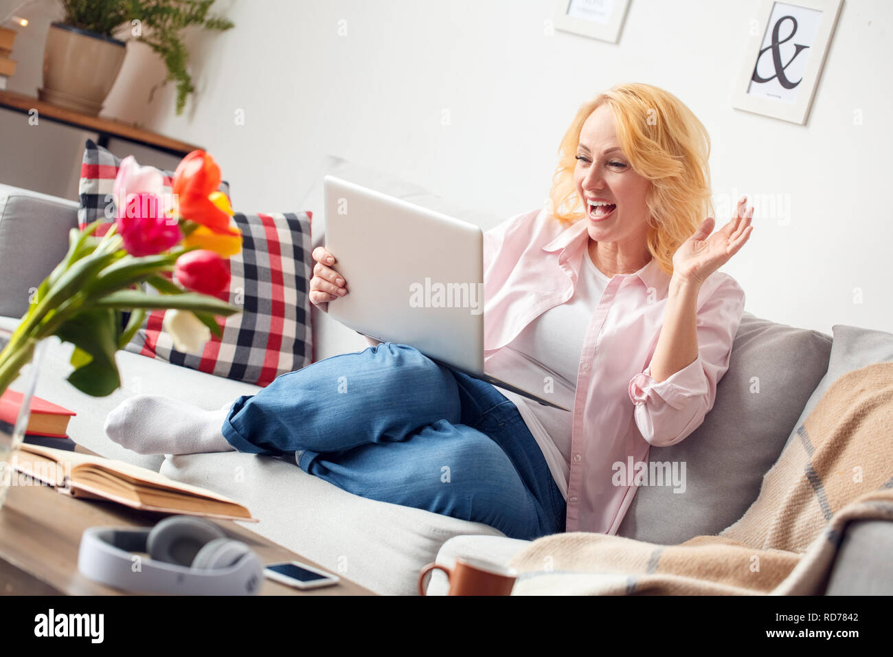 Senior woman at home sitting having video call on laptop smiling cheerful Stock Photo